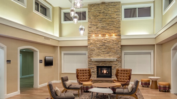 A spacious living room with a fireplace, comfortable seating, and a high ceiling.