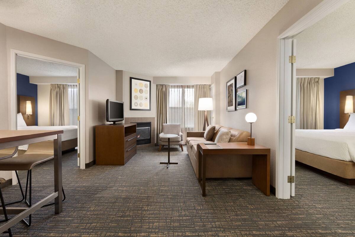 A hotel room with a bed, a desk, a sofa, a TV, and a fireplace.