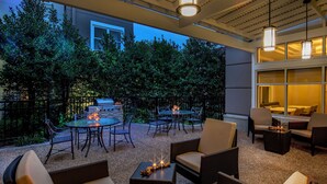 An outdoor patio area with wicker furniture, a round table, and candles.