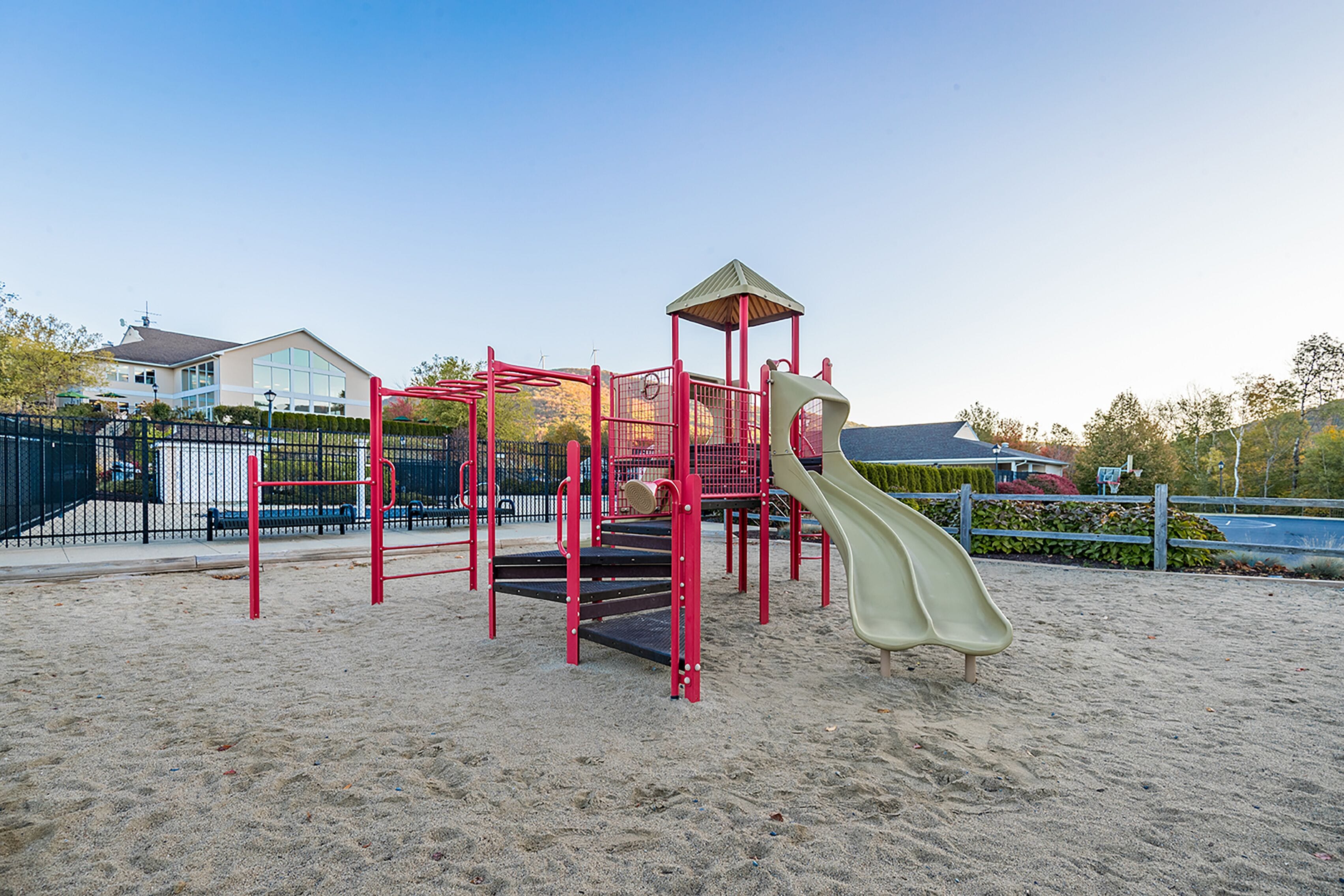 A playground with a slide, climbing structures, and a covered area.