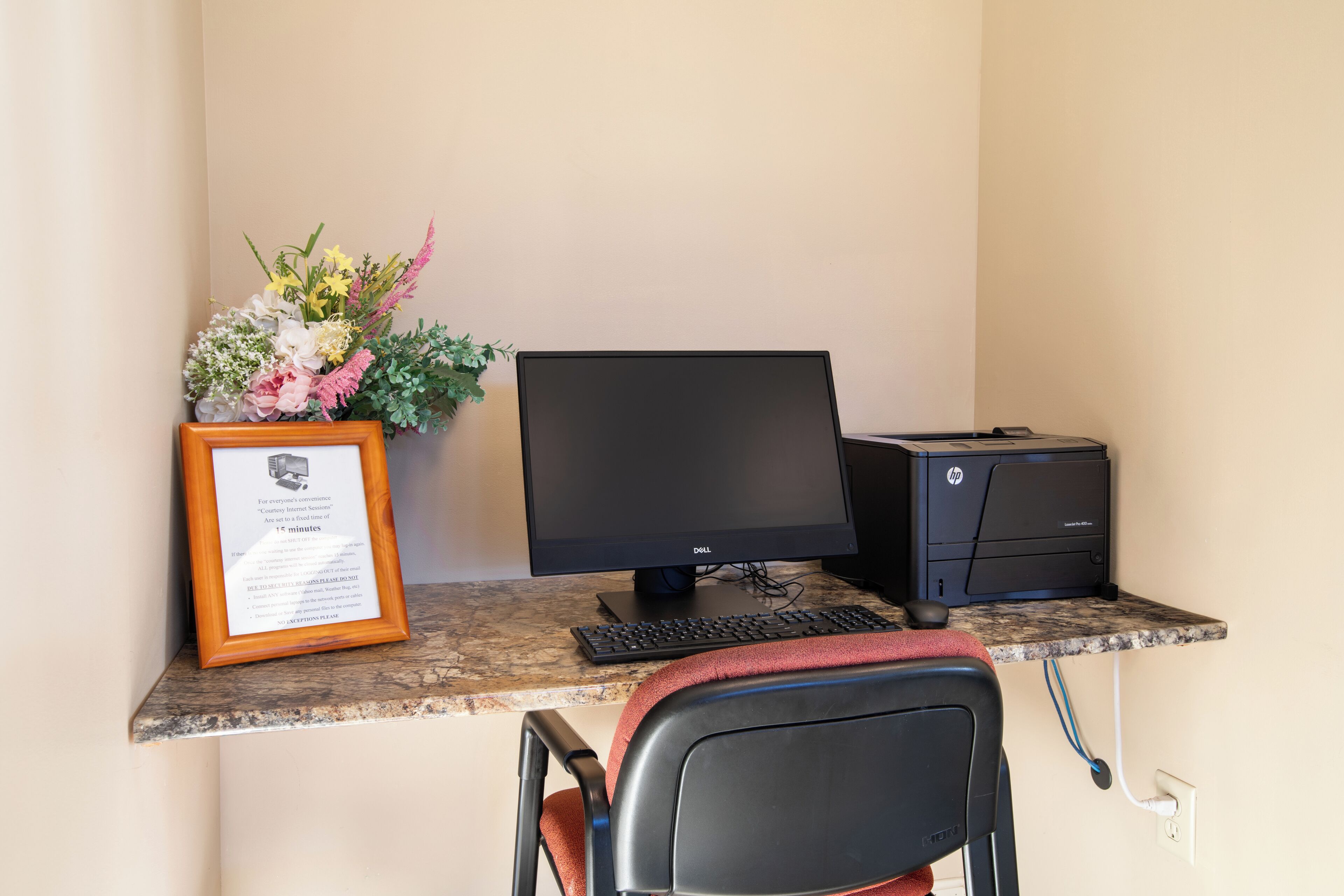 A desk with a computer, printer, and framed certificate.
