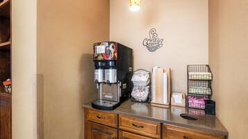 A kitchenette with a coffee machine, a wall-mounted light, and storage shelves.
