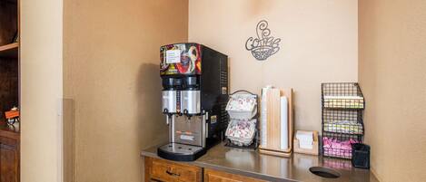A kitchenette with a coffee machine, a wall-mounted light, and storage shelves.