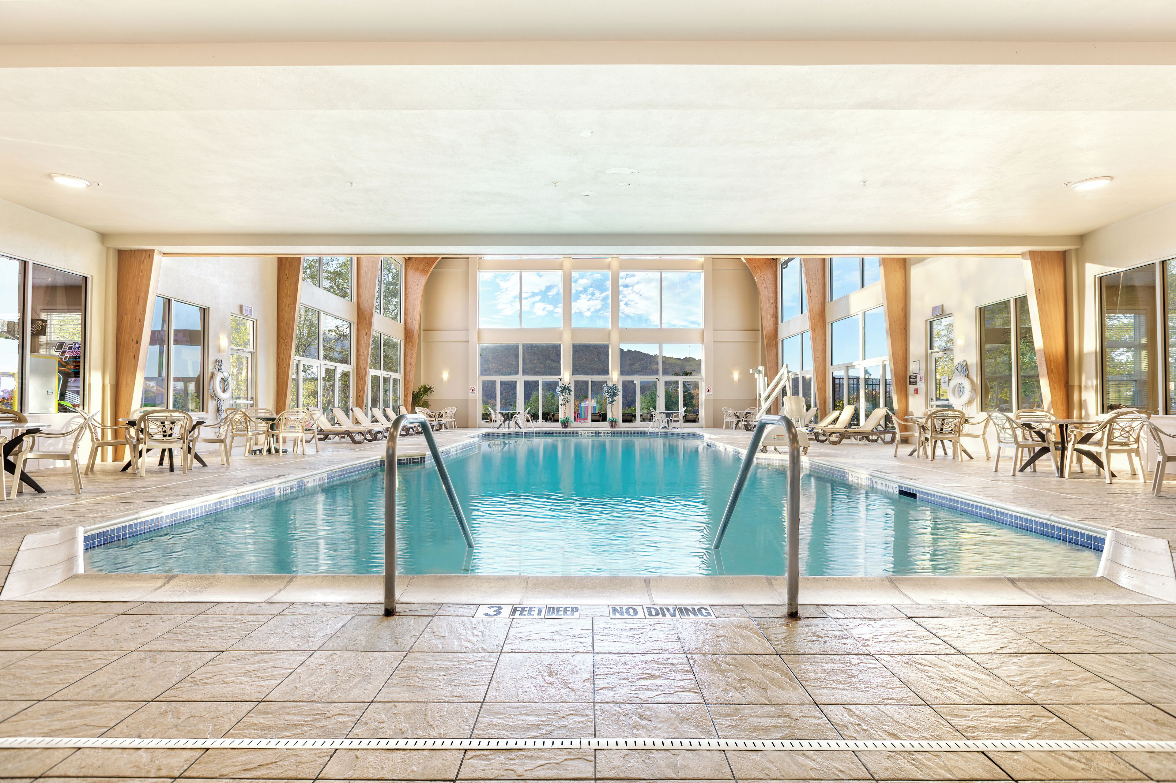 Una piscina interior amb indicadors clars, gandules i vistes a les muntanyes a través de grans finestres.