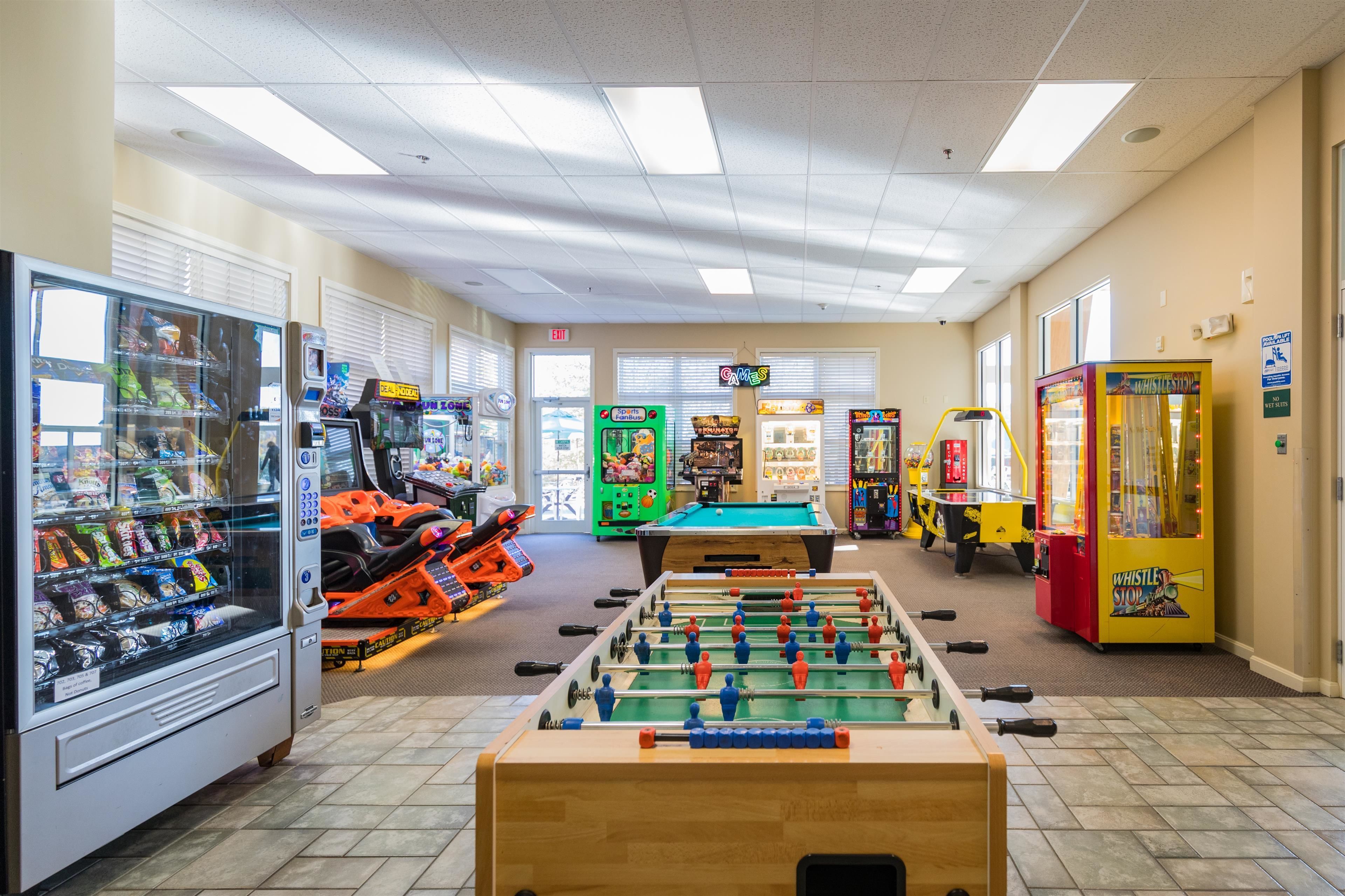 A room with a foosball table, vending machines, and arcade games.
