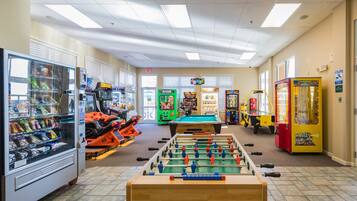 A room with a foosball table, vending machines, and arcade games.