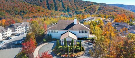 Un hôtel doté d’un belvédère central, entouré d’un parking et de feuillages d’automne.