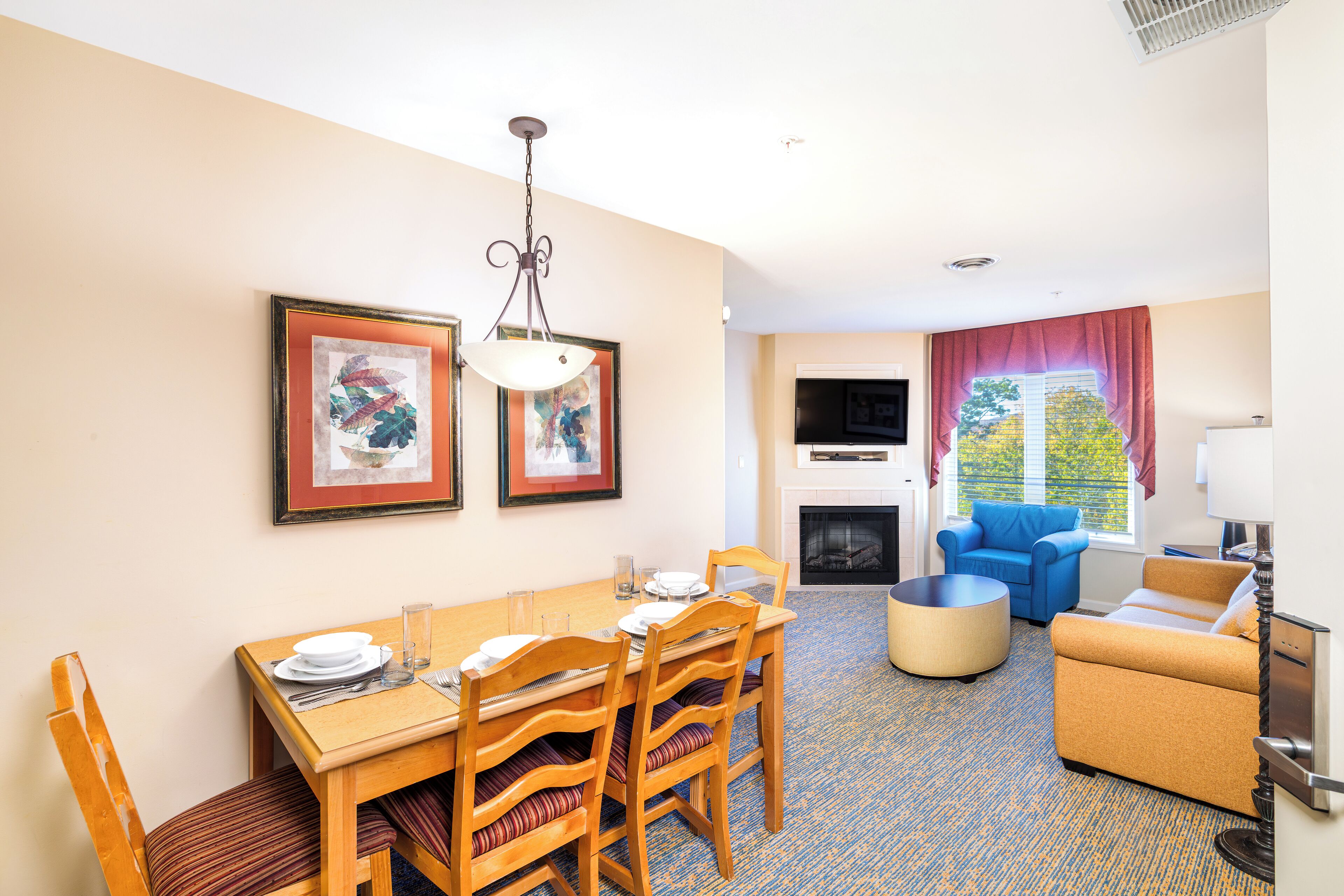 A dining area with a wooden table set for four, a blue sofa, and a fireplace.