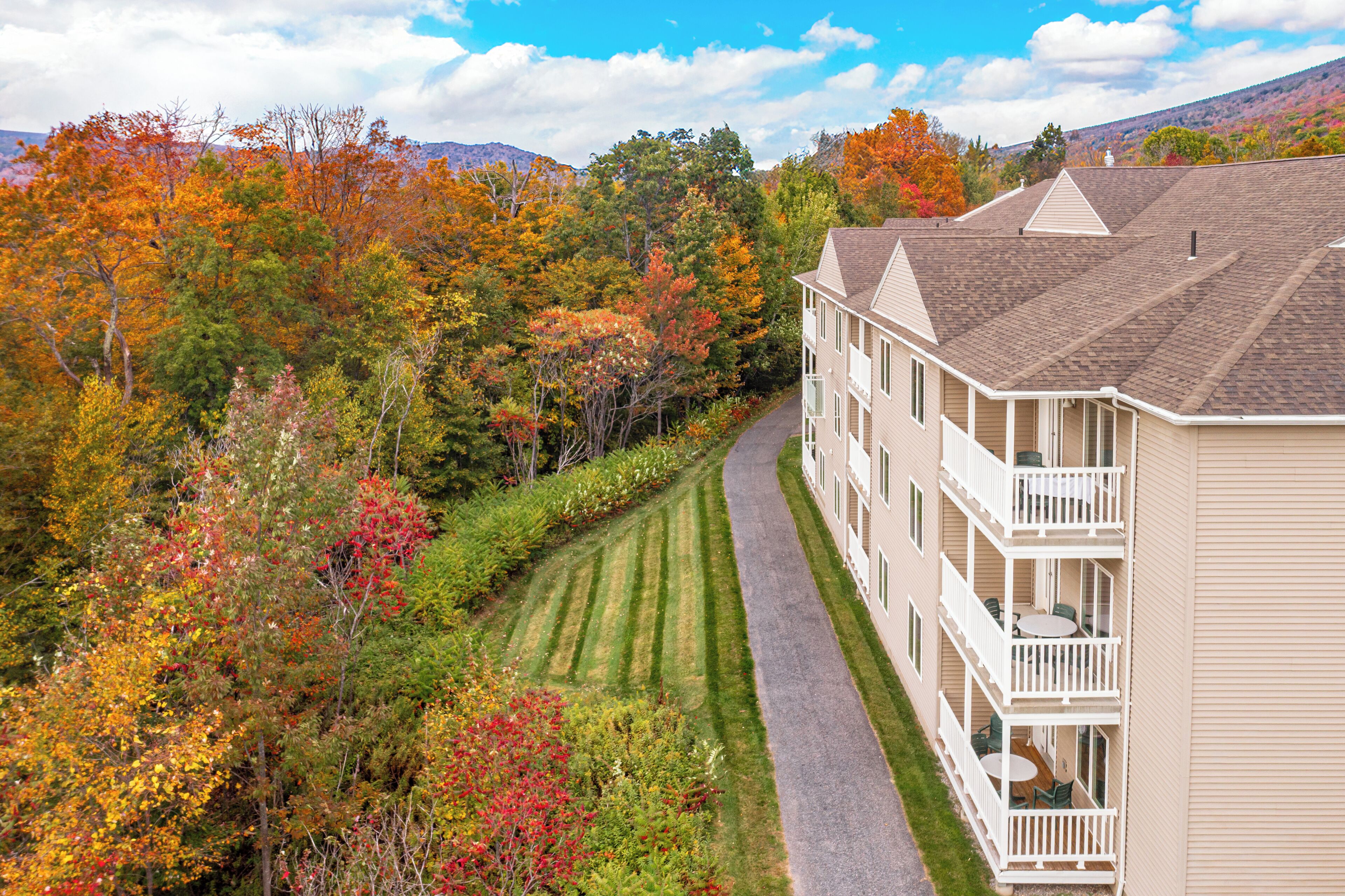 A multi-story building with a central courtyard, surrounded by a landscaped garden and autumn-colored trees.