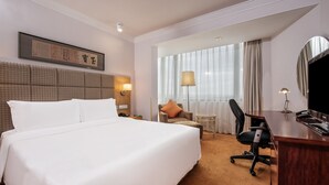 A hotel room with a large bed, a desk, a chair, a lamp, a TV, and a window with curtains. - Holiday Inn Beijing Temple Of Heaven by IHG (Beijing)