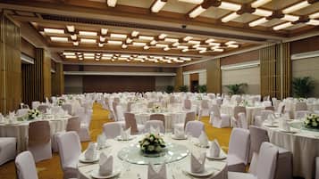 Un salón de banquetes con mesas redondas dispuestas para un evento formal, con manteles blancos y sillas.