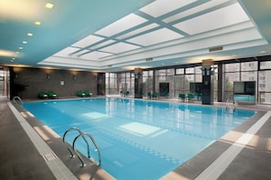 An indoor swimming pool with clear blue water, surrounded by lounge chairs and a glass ceiling. - Holiday Inn Beijing Temple Of Heaven by IHG (Beijing)