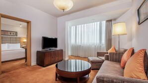 A hotel room with a bed, a TV, a round coffee table, a sofa, and a large window with curtains. - Holiday Inn Beijing Temple Of Heaven by IHG (Beijing)