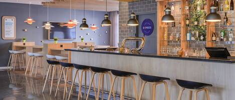 A bar area with stools, a counter, and a variety of bottles and glasses.