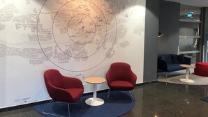A modern lounge area with a large map on the wall, red seating, and a small round table. - Holiday Inn Express Frankfurt Messe by IHG (Frankfurt)