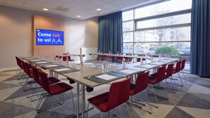 A conference room with a large screen displaying 'Come talk to us!' and a view of the street outside. - Holiday Inn Express Frankfurt Messe by IHG (Frankfurt)