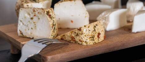 A wooden board with various cheeses and a fork.