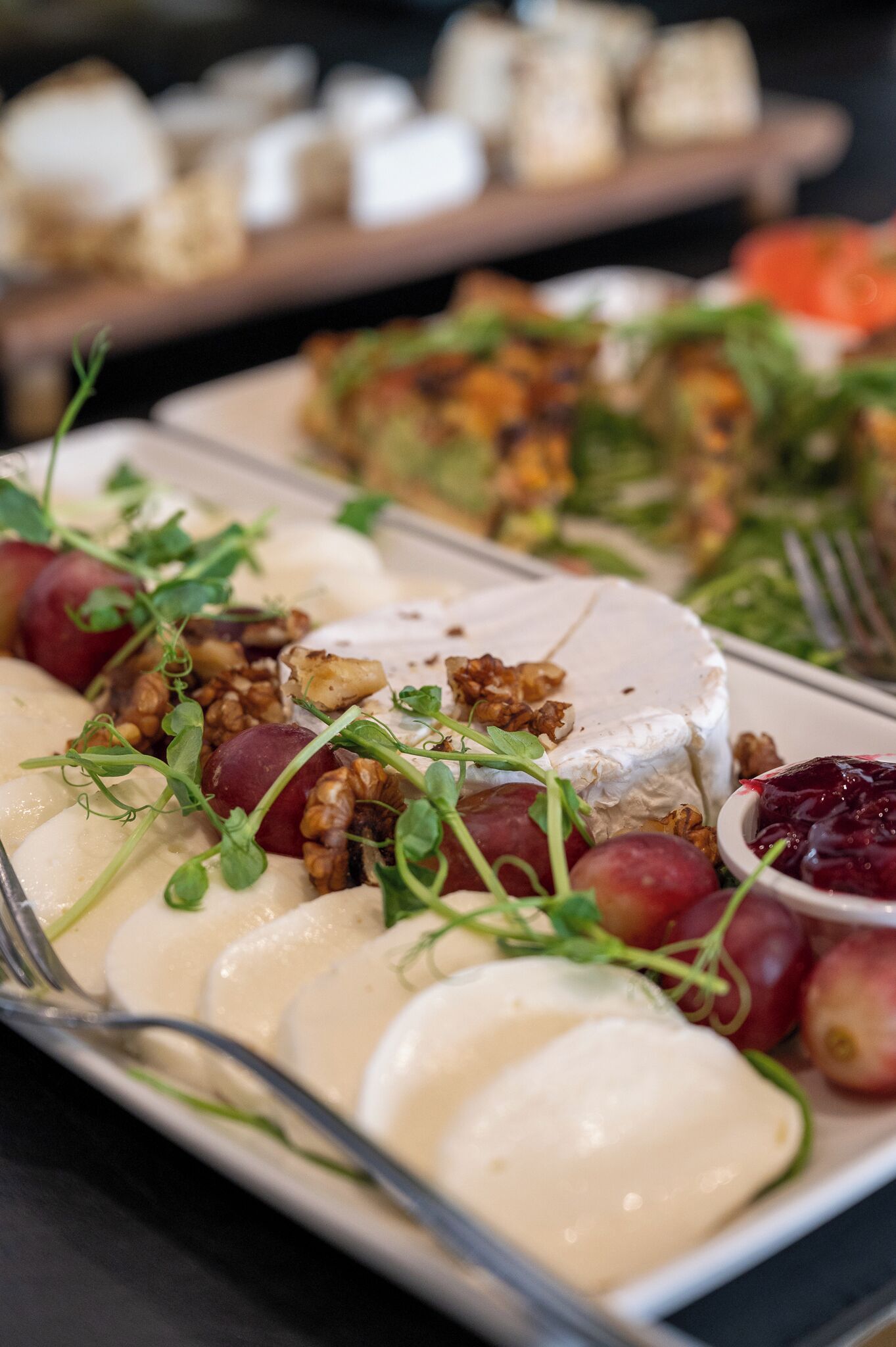 Une planche de charcuterie accompagnée de différents fromages, de fruits et de noix.