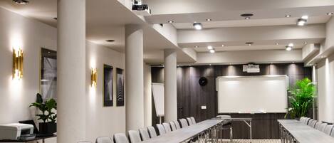 A conference room with a long table, chairs, a whiteboard, and a projector.