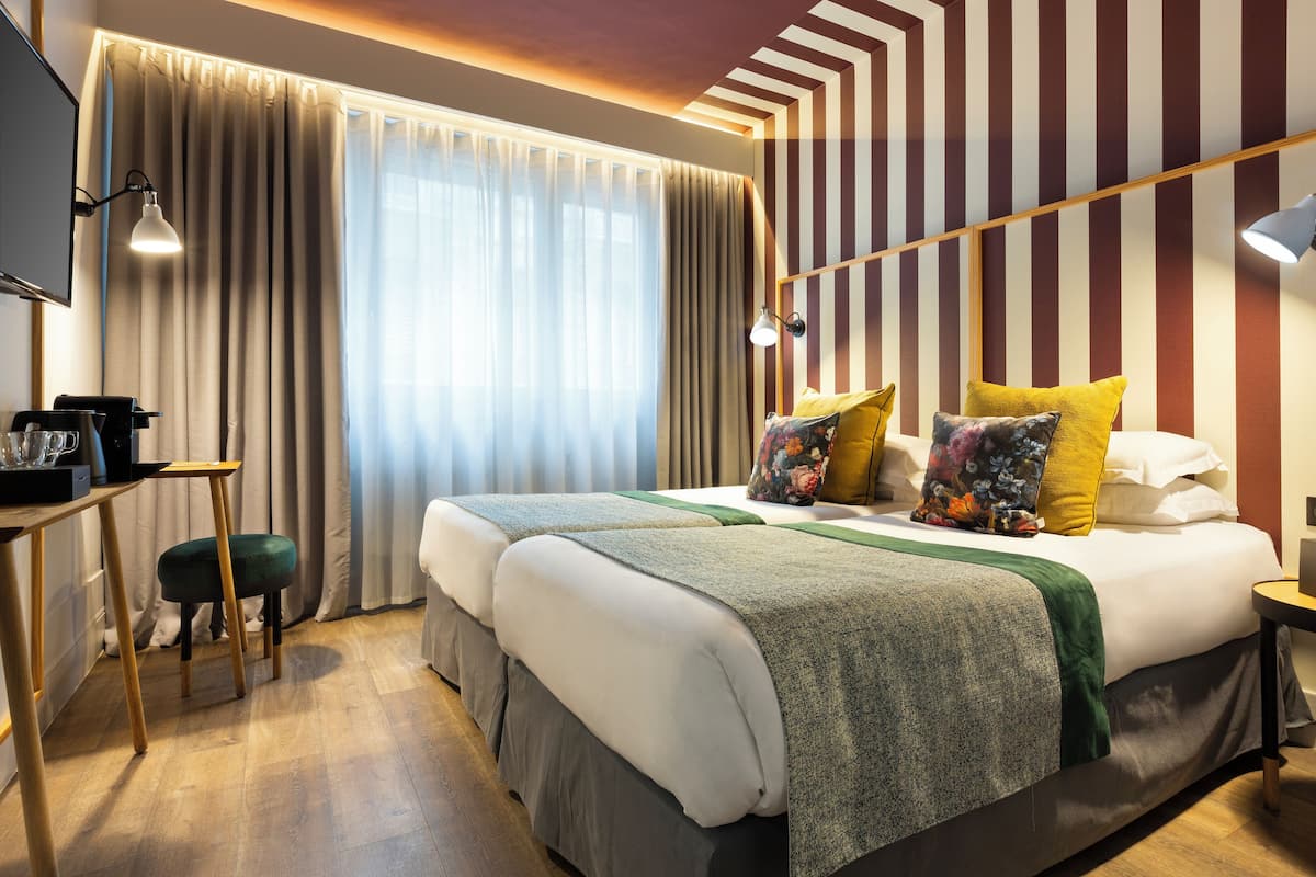 Une chambre d’hôtel avec un grand lit, deux tables de chevet, un bureau et une chaise.