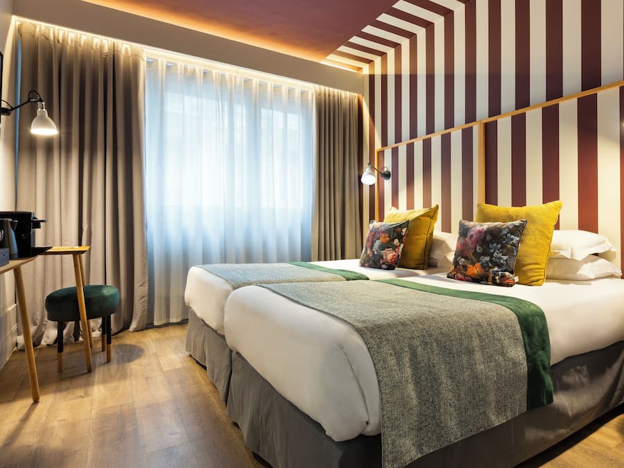 A hotel room with a large bed, two bedside tables, a desk, and a chair.