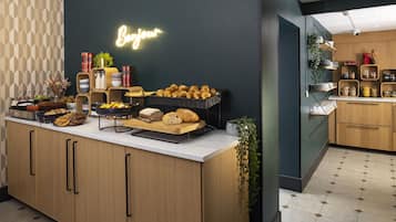 A modern kitchen with a wooden counter, various baked goods, and a neon sign.