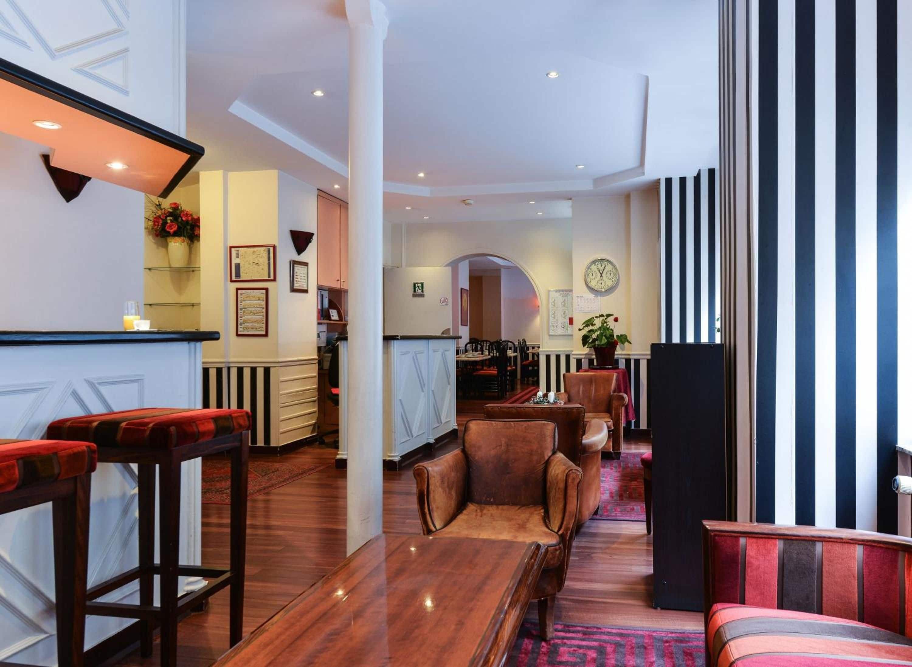 A spacious living area with a wooden floor, a sofa, a coffee table, and a bar area with stools.
