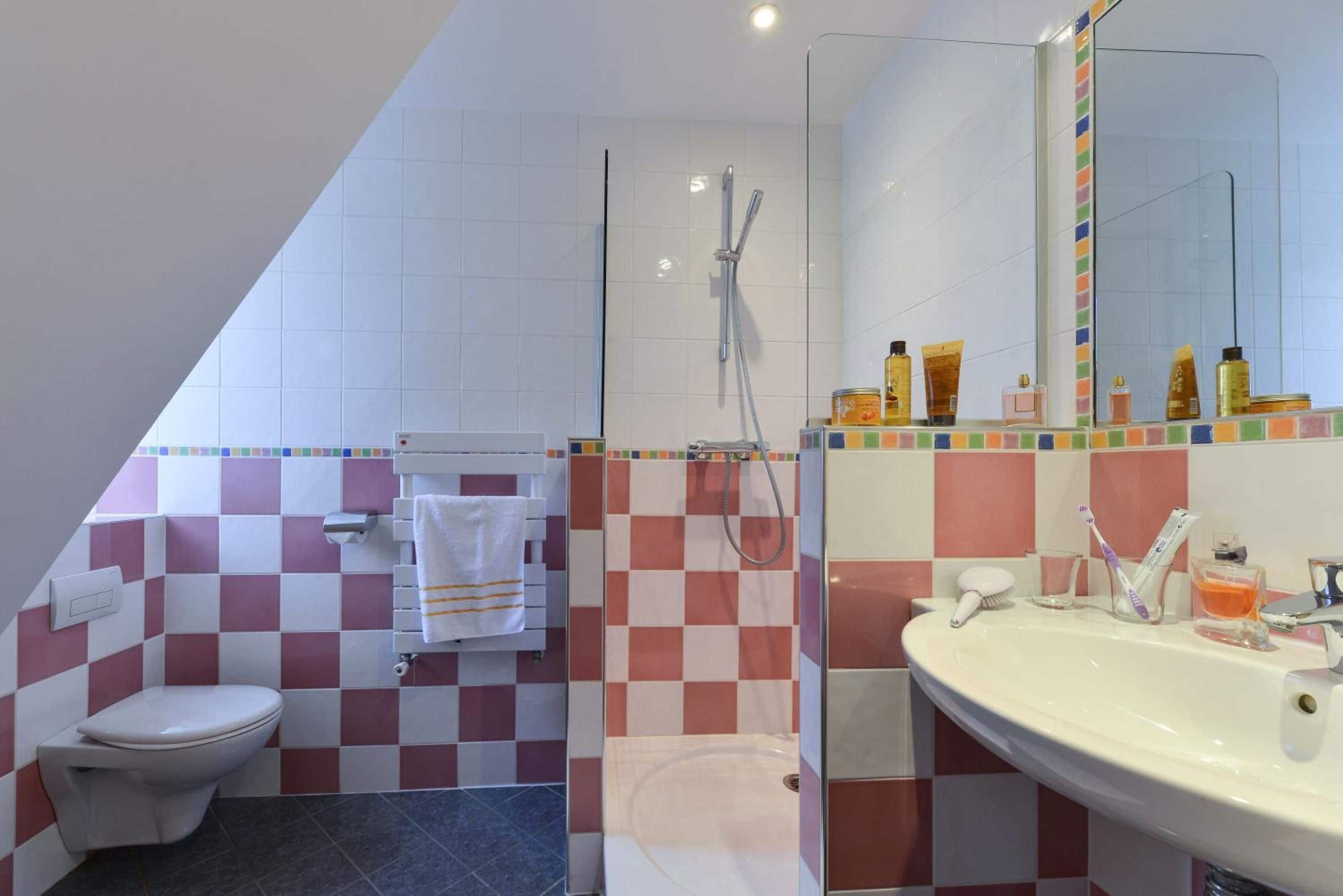 A bathroom with a toilet, shower, and sink.