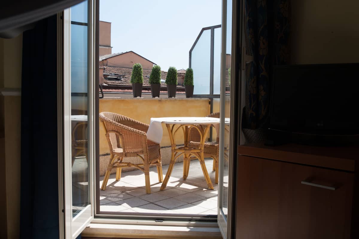 Un balcon agrémenté de meubles en osier et de plantes en pot.