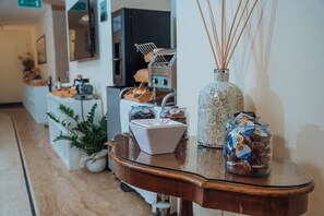 Une table à plateau en verre, sur laquelle se trouvent une boîte blanche, un vase décoratif et un bocal de chocolats.