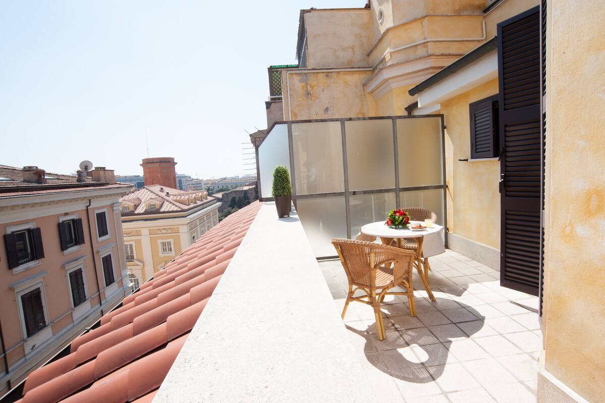 Un balcon avec une table et des chaises, un pot de fleurs et une vue sur le paysage urbain.