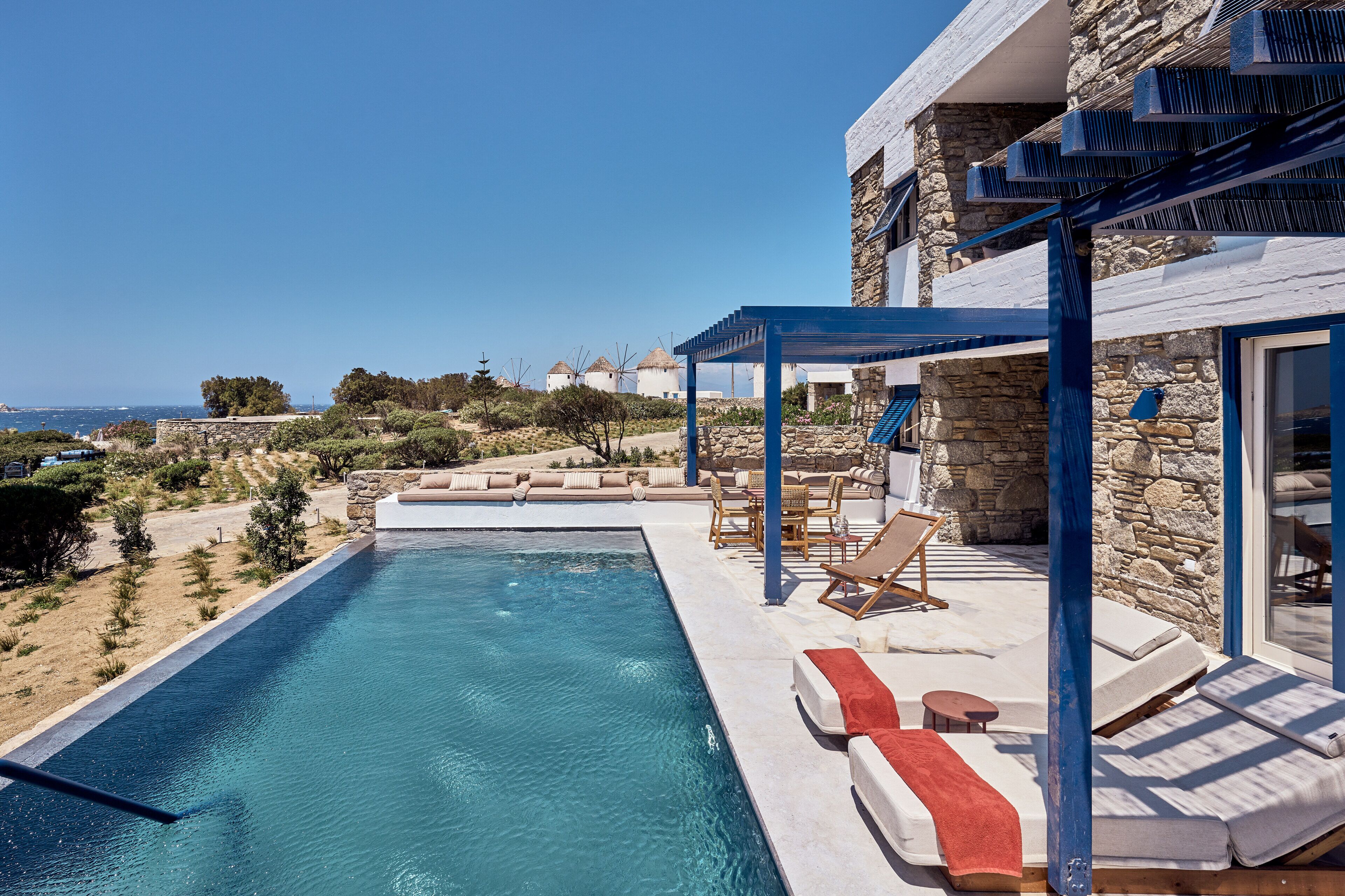 Un área junto a la piscina con sillones de descanso y un edificio de piedra.