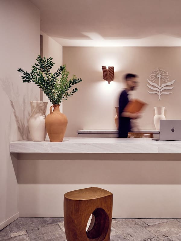 Welcome to our reception area, featuring a minimalist design with a reception desk, potted plant, and comfortable stools.