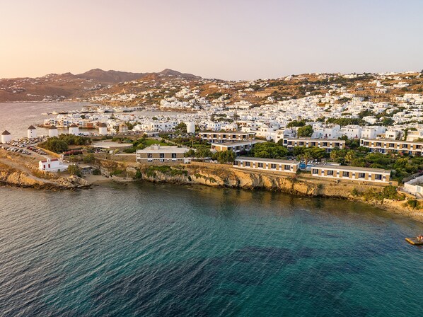 A coastal town with white buildings, a marina, and a rocky shoreline. - Mykonos Theoxenia, a Member of Design Hotels (Mykonos)
