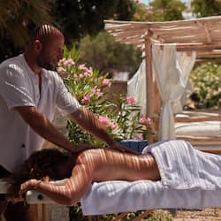 Experience a rejuvenating massage in a serene outdoor setting surrounded by lush greenery and blooming flowers.