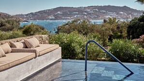 A pool area with a view of the sea and a hillside.
