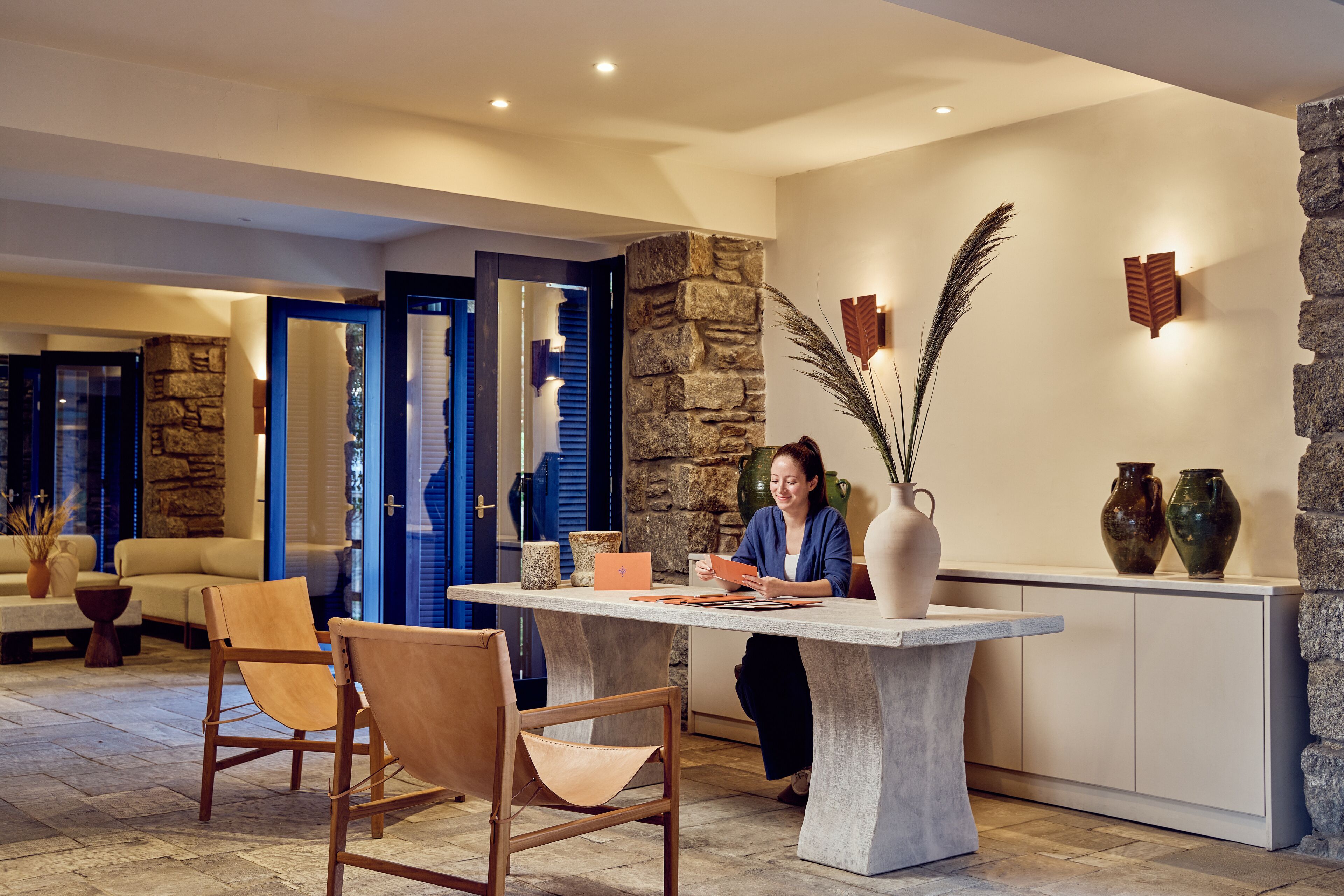 A reception area with a stone wall, a reception desk, and a seating area with chairs and a sofa.