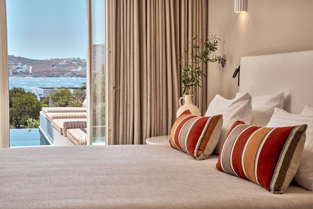 A bedroom with a large bed, a view of the sea, and a balcony with a sofa.