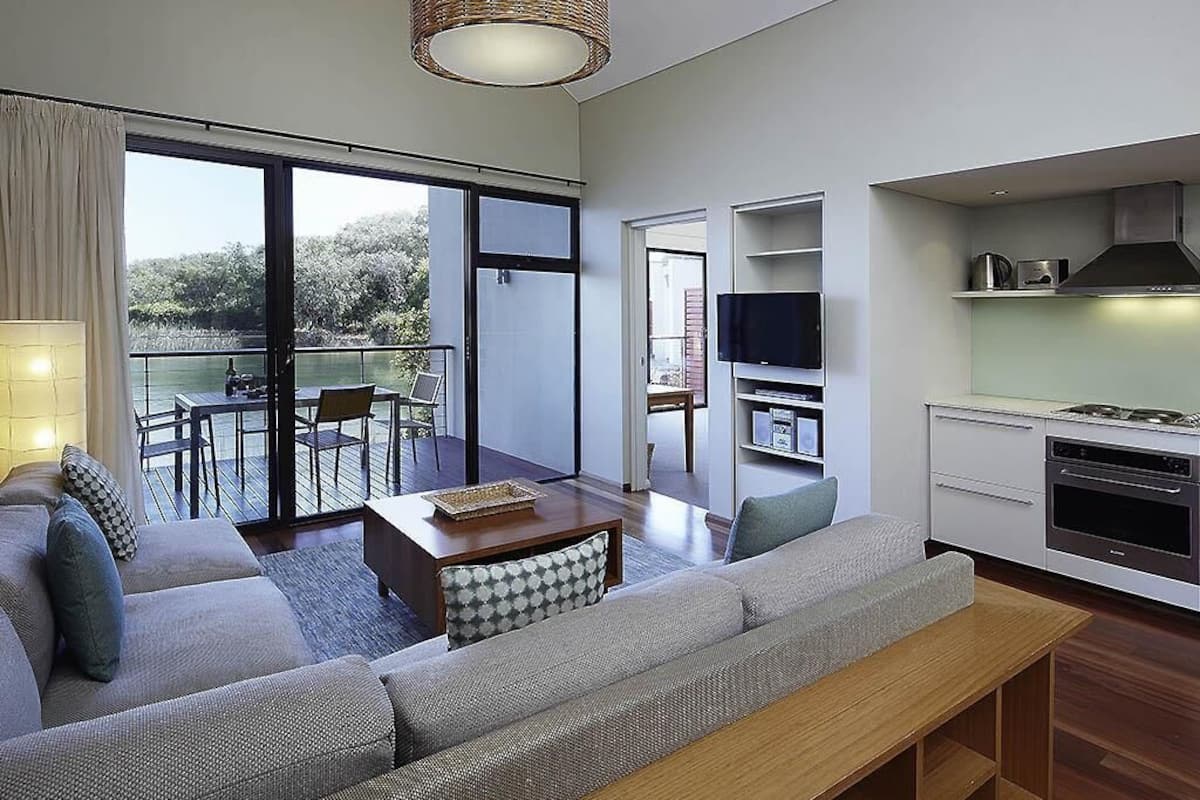 Una sala de estar moderna con un sofá, una mesa de comedor, un televisor y una zona de cocina.
