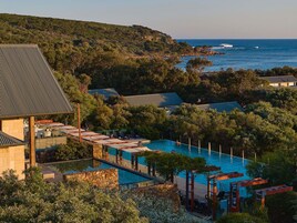Un resort con piscina, sillas de descanso y vista al océano.