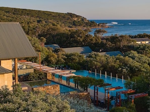 Un resort con piscina, sillas de descanso y vista al océano.