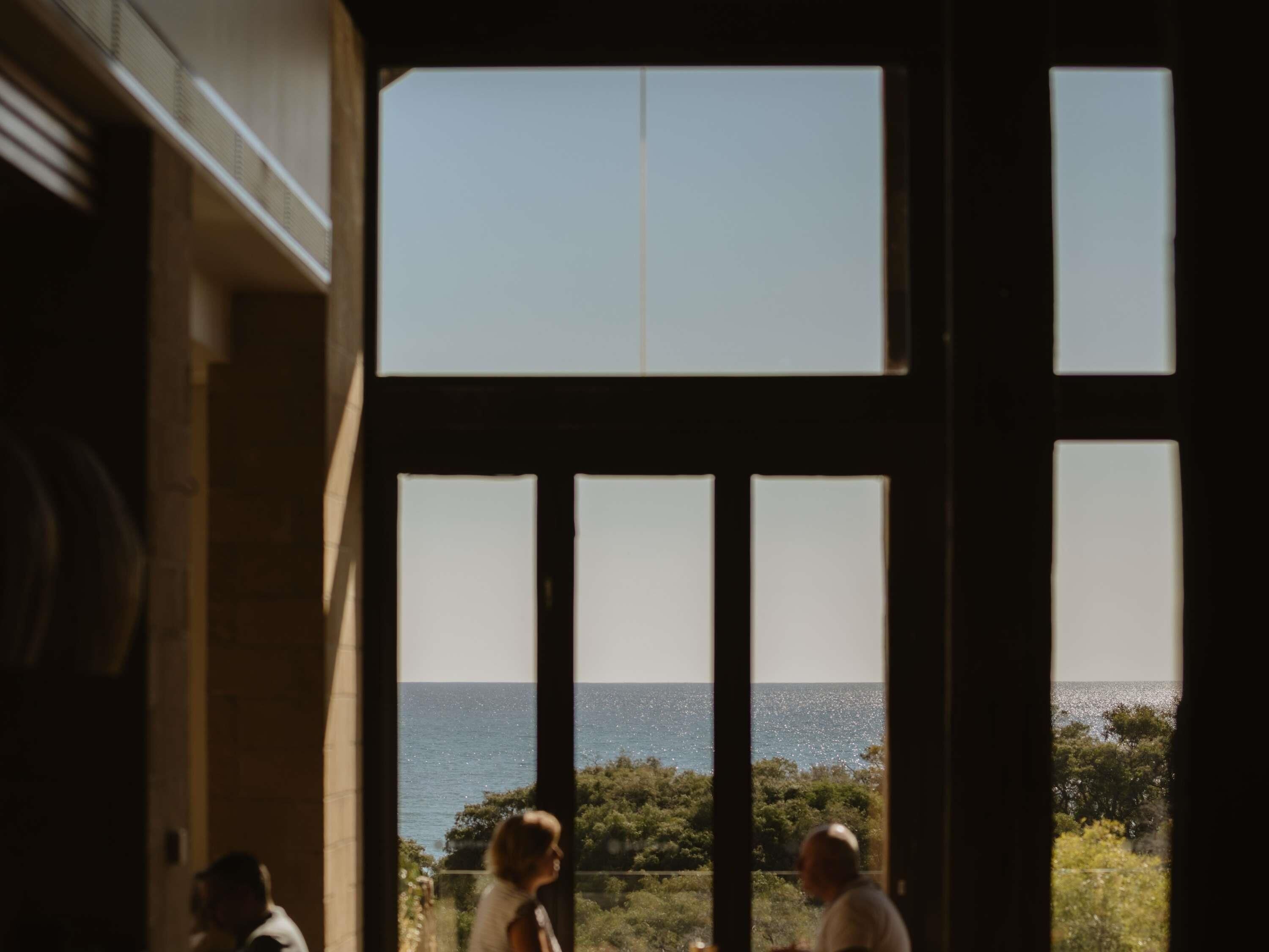 A room with large windows overlooking a body of water and greenery.