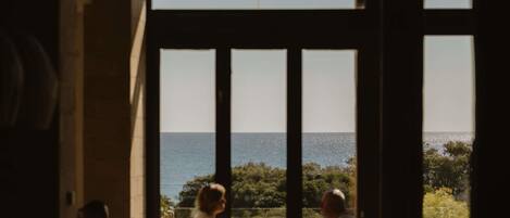 A room with large windows overlooking a body of water and greenery.