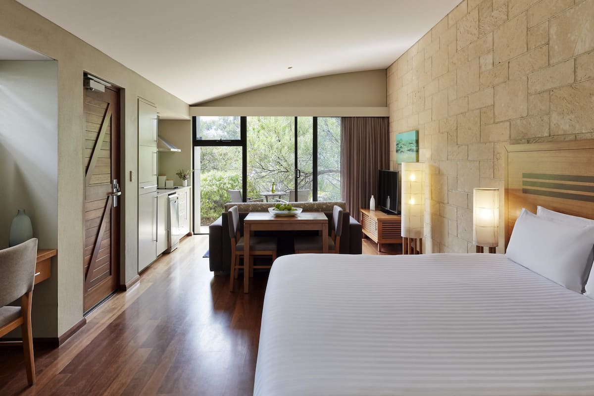 Habitación de hotel con cama, mesa de comedor, televisión y vista al exterior.