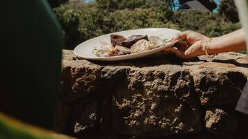 A person holding a plate with food on a stone ledge.