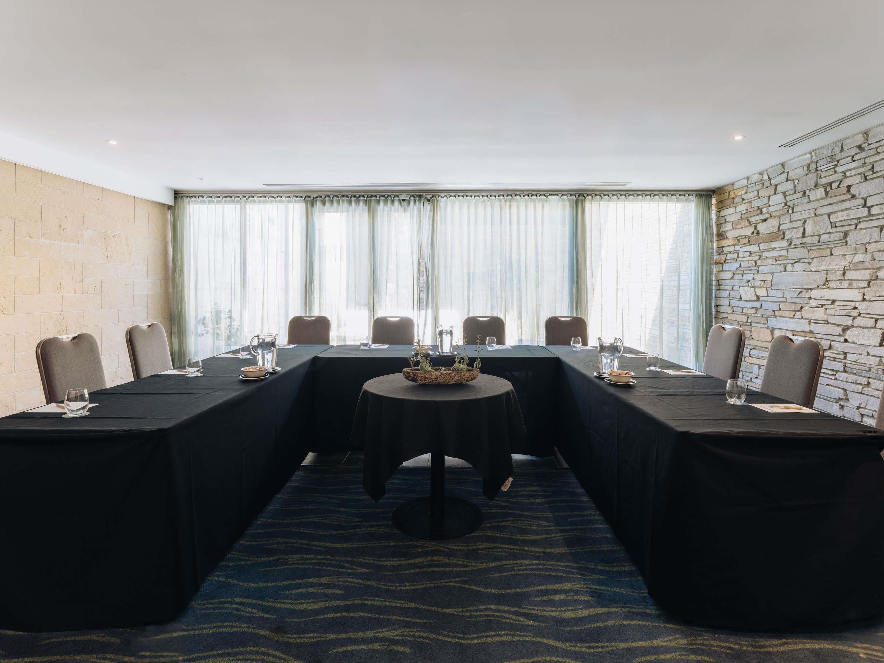 A conference room with a long table, chairs, and a stone wall.