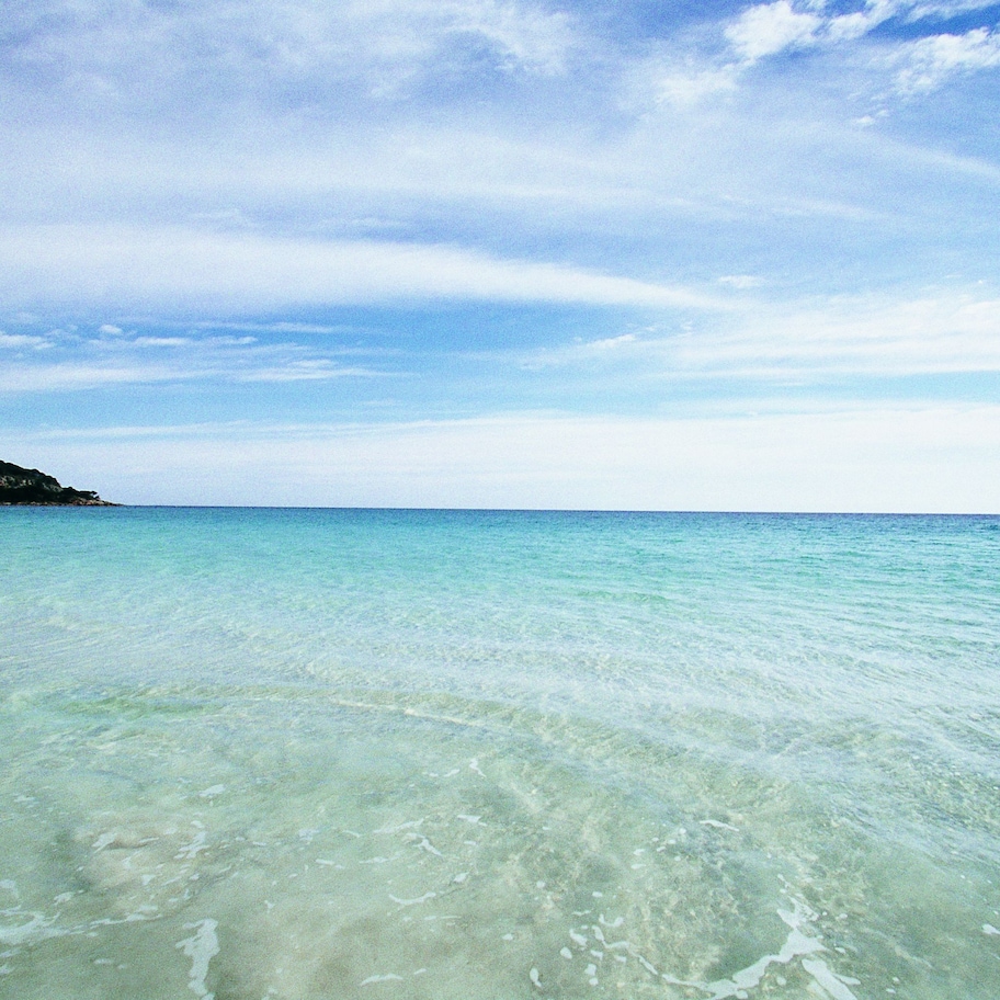 A clear view of a beach with calm waters and a distant landmass.