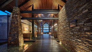 Un edificio moderno con fachada de piedra, techo de madera y entrada de vidrio.