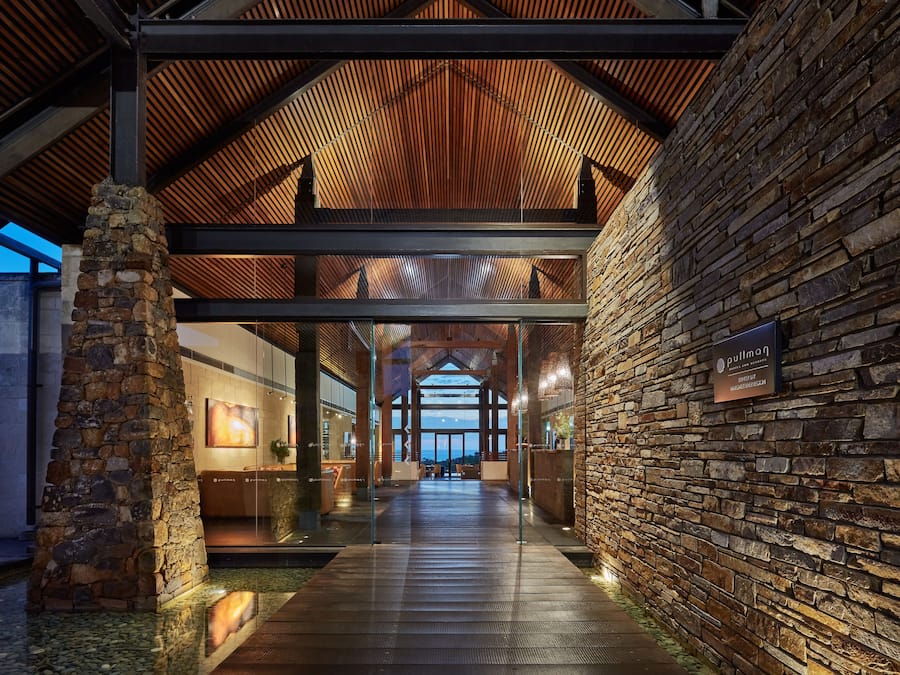 A modern building with a stone facade, a wooden ceiling, and a glass entrance.