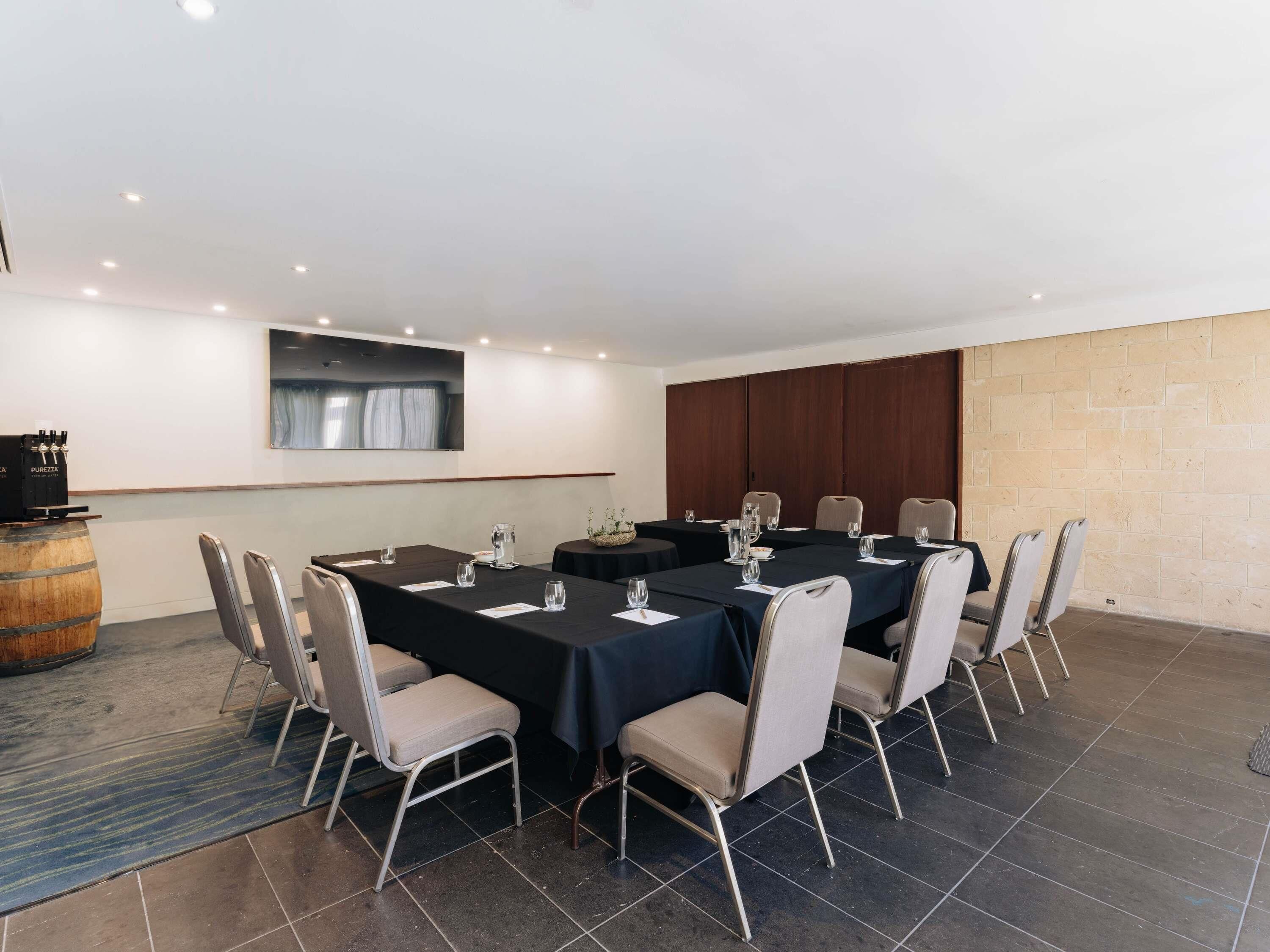 A conference room with a long table, chairs, and a wooden barrel.